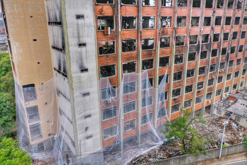 Operários da empresa demolidora passam tela através da abertura das janelas, envolvendo a estrutura até o quarto andar - Foto: Divulgação FBI Demolidora