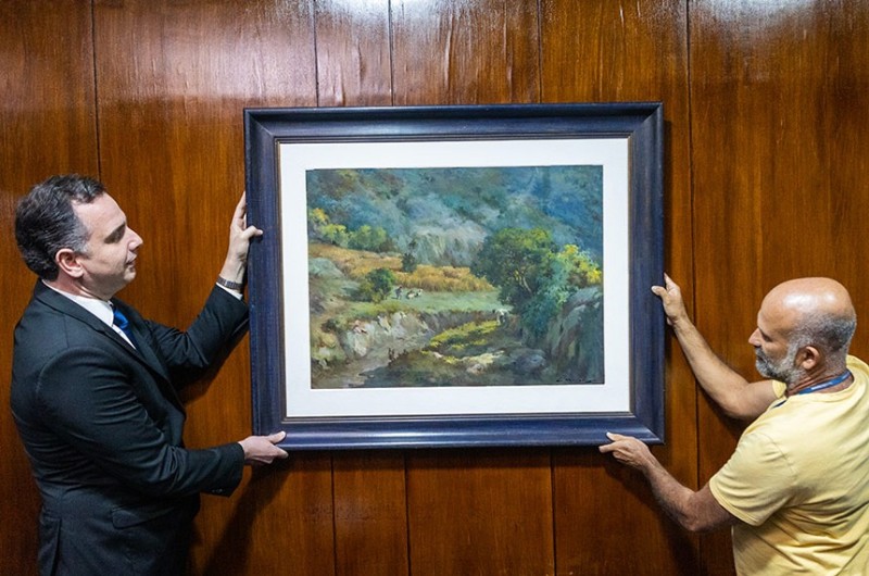 Pacheco e um servidor do Senado recolocam o quadro Trigal na Serra na recepção da Presidência da Casa. A obra foi danificada por vândalos durante invasão do Congresso por vândalos - Pedro Gontijo/Senado Federal