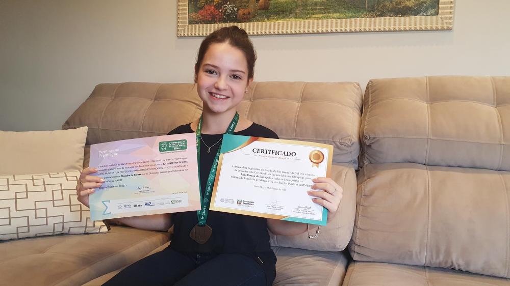 A medalha de ouro ainda não está em suas mãos, mas enquanto isso, Júlia já coleciona três reconhecimentos pela sua dedicação aos estudos. Crédito: Renata Oliveira/NB